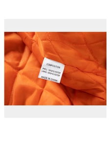 Detailed macro shot of orange quilted lining and 100% polyester care label on jacket