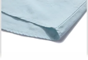 Detail of light blue cotton linen shirt curved hem with double needle stitching finish