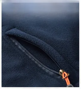 Detail van donkerblauw fleece vest met zijzak en contrasterende oranje ritstrekker voor heren