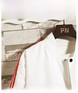 Detail view of white jacket featuring red shoulder stripes and ribbed stand-up collar