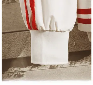 Detail of white sports jacket cuff with elastic ribbed design and three red side stripes