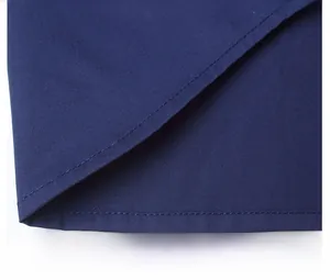 Detailed macro view of dark blue shirt fabric showing fine twill weave and neat hem stitching