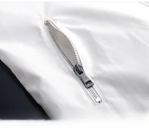 Dettaglio giacca bianca con tasca con zip in metallo argentato e logo Vogue inciso
