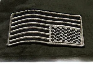 Detailed embroidery on a dark olive green military jacket showing striped cross patterns