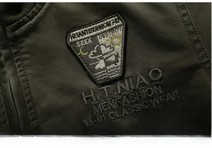 Close-up of olive green military jacket showing detailed embroidery and shield badge
