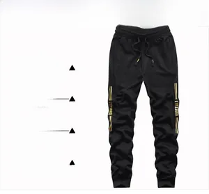 Detail of black jogger pants with golden side stripes and Freedom typography print