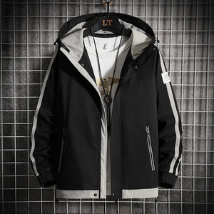 Men's casual hooded jacket in black and beige contrast panels hanging on industrial mesh