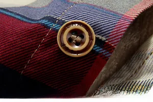 Gros plan détaillé d'un bouton marron à quatre trous sur une chemise à carreaux