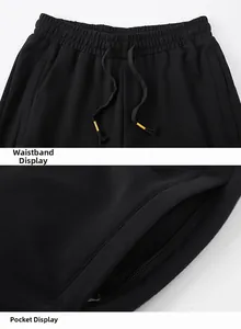 Detail view of men's black sports pants with elastic waistband and zipper pockets