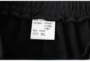 Detail of care label on black outdoor pants showing fabric composition and fine stitching