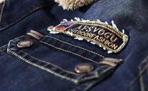 Detail of denim jacket featuring chest pocket with embroidered patch and warm fleece lining