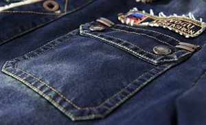 Detail of a denim jacket featuring embroidered patches and retro metal buttons