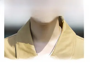 Detailed close-up of khaki cotton jacket collar with a silver metal twisted chain necklace