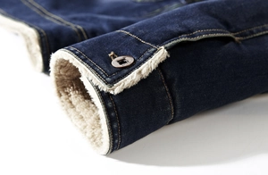 Detail of denim jacket cuff with warm white fleece lining and engraved metal button