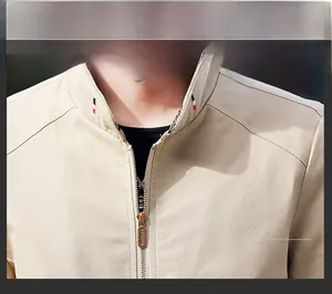 Detail view of khaki cotton jacket with stand collar, tri-color tape and metal zipper