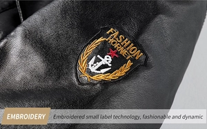 Detail of custom embroidery badge on black PU leather jacket featuring golden laurel leaves