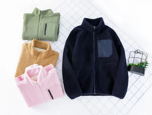 Detail of fleece jackets in navy, green, yellow, and pink with zip chest pockets