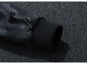 Dettaglio del polsino elastico a costine e del tessuto in nylon della giacca bomber nera