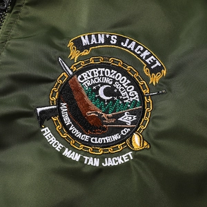 Détail macro de la broderie de haute densité sur le blouson aviateur en nylon vert pour hommes
