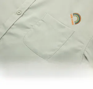 Detail of light green shirt showing a single chest pocket and rainbow embroidery