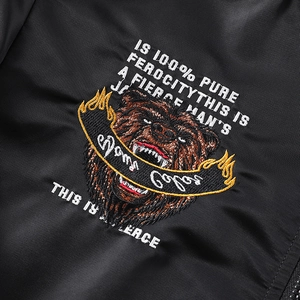 Gros plan d'une broderie d'ours avec texte Pure Ferocity sur veste bomber noire