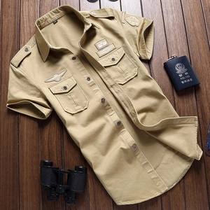 Camicia militare kaki a maniche corte con toppe da pilota e tasche su sfondo legno