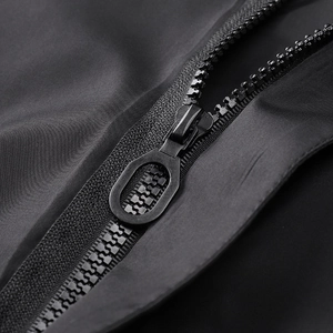 Detail of matte black jacket with a large hollow oval metal zipper head and smooth fabric