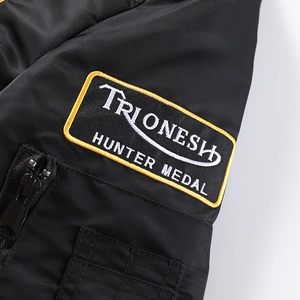 Détail de l'écusson TRIONESH brodé et poche zippée sur la manche de la veste bomber noire