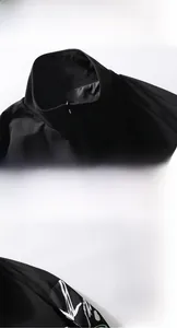 Détail d'une veste noire à col montant avec tissu résistant et fermeture éclair en métal