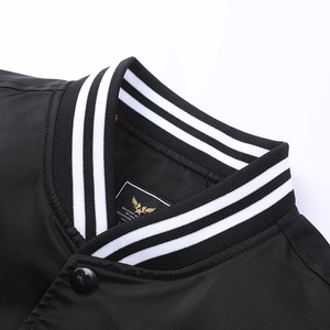 Detail of striped ribbed collar and golden eagle label on black nylon flight jacket