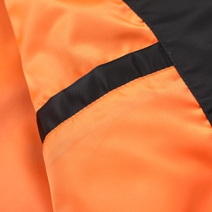 Detailed close-up of vibrant orange nylon fabric with precision stitching on bomber jacket