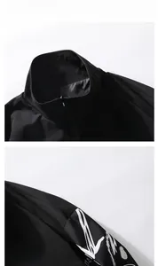 Détail d'une veste noire à col montant avec imprimé graffiti blanc et zip métallique
