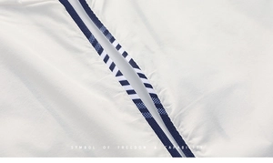 Macro detail of white sun protection jacket showing blue zipper and striped webbing trim