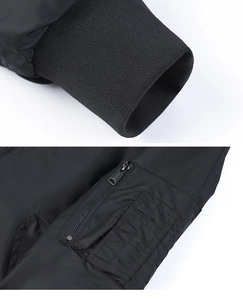 Detailed view of black bomber jacket ribbed cuffs and utility arm pocket with metal zipper