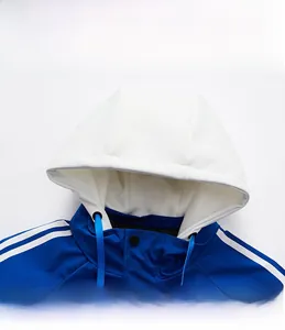 Detail shot of blue sporty jacket showing the detachable white hood and button collar