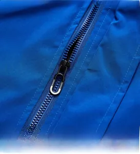 Detailed macro view of a durable black custom metal zipper on a blue windproof jacket