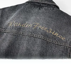Dettaglio ravvicinato del ricamo 'Wander Free since' su giacca di jeans grigio lavato