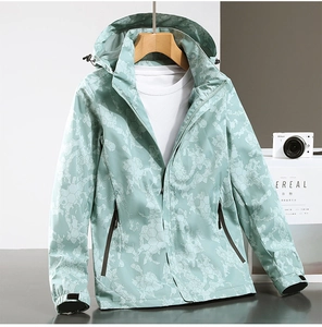 Macro view of mint green windbreaker with hexagonal camo pattern and drawstring hood