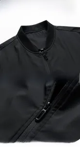Detail of a black men's jacket showing ribbed collar, durable zipper and stitching