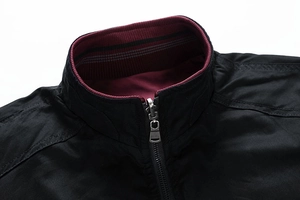 Detail of men's jacket with black fabric, burgundy ribbed collar, and silver metal zipper