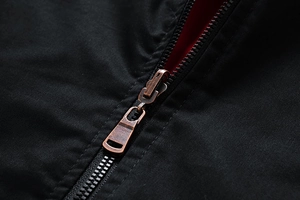 Close-up of vintage bronze zipper and red lining on a black reversible jacket