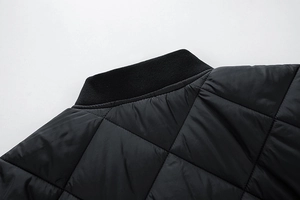 Close-up of quilted diamond pattern and ribbed collar on black winter jacket