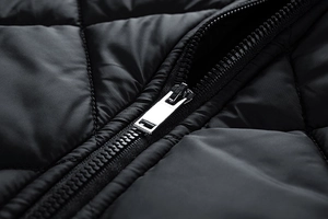 Macro detail of high-quality silver metal zipper on a black quilted diamond jacket