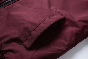 Detailed view of the dark burgundy jacket's diagonal pocket and precise stitching details