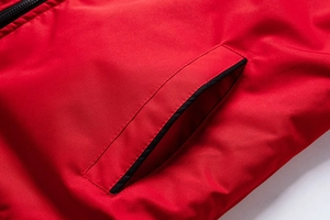 Close-up detail of red jacket side pocket with black trim and durable stitching