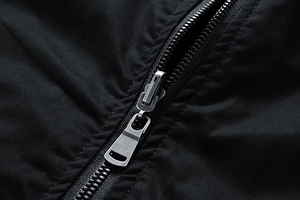 Detailed close-up of a silver metal zipper on a premium black cotton jacket fabric