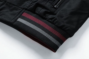 Detailed view of black jacket ribbed cuffs with red and grey contrasting stripes