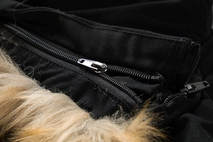 Detail of durable metal zipper on black winter jacket with brown faux fur collar texture