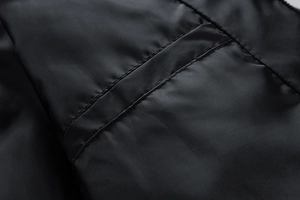 Close-up detail showing precision stitching on black synthetic fabric of winter jacket