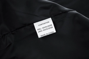Close-up of garment wash label showing 100% polyester composition and care instructions
